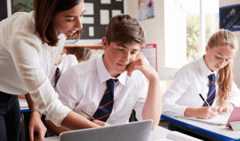 Internal audit for academies - time for change - School teacher with struggling student in classroom