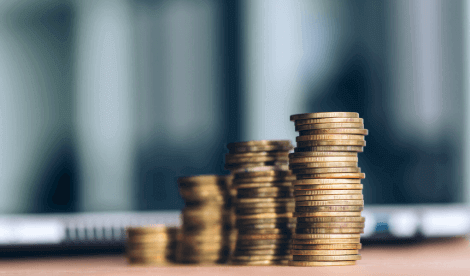 Coins in increasing piles next to laptop