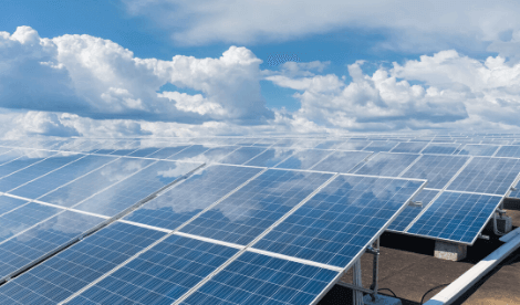 Solar panels on top of roof with blue sky to signify environmental reporting