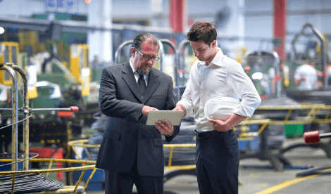 Professional workers in manufacturing environment conducting visit with tablet device