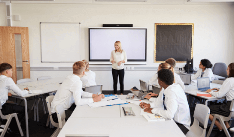 Happy teacher talking to students in classroom