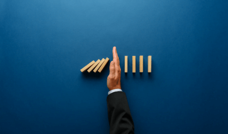 Hand stopping falling dominoes